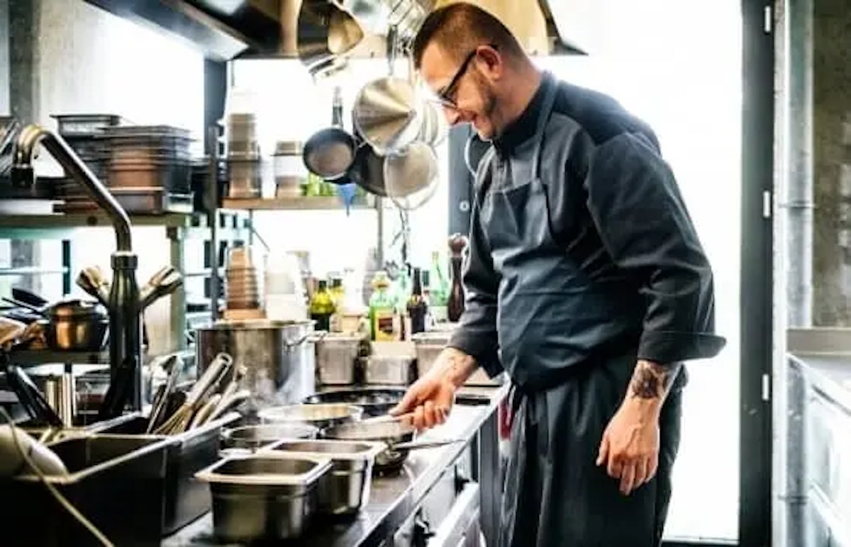 Man in apron cooking back of house